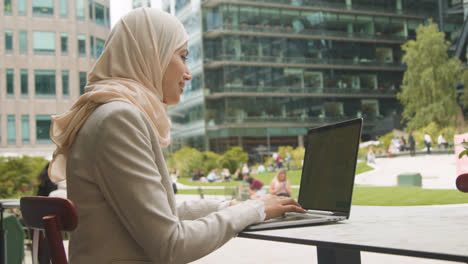 Muslimische-Geschäftsfrau-Sitzt-Draußen-In-Stadtgärten-Und-Arbeitet-Am-Laptop-1